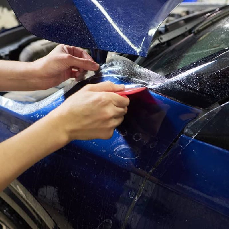 worker-applies-protective-film-antigravity-protective-coating-car-headlight-details-car